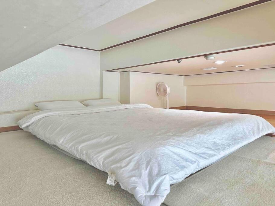 ein Schlafzimmer mit einem großen Bett mit weißer Bettwäsche in der Unterkunft Gasan Duplex - Female Only in Seoul