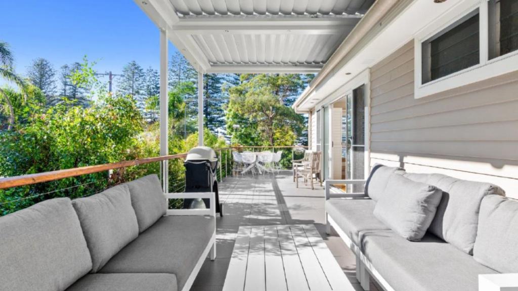 a patio with couches and a table on a house at Marley's Retreat - Patonga Beach in Patonga Beach