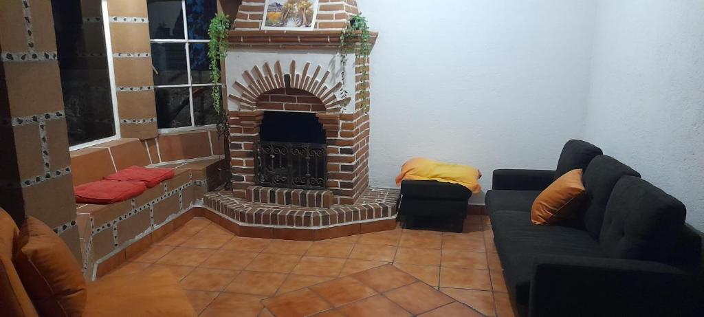 sala de estar con chimenea de ladrillo y 2 sofás en Casa Sauces en Tepoztlán