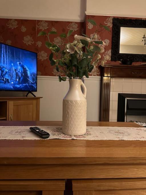 un vase avec des fleurs sur une table et une télécommande dans l'établissement Carlisle The Cathedral City And Gateway In Cumbria, à Carlisle