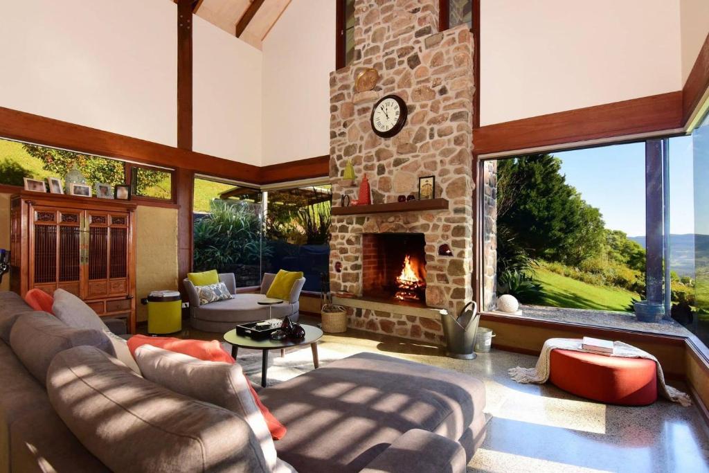 sala de estar con sofá y chimenea en Womberroo, Kangaroo Valley, en Bellawongarah