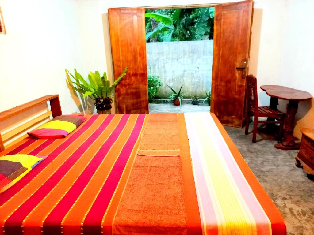 Mount Rest Villa في هيكادوا: غرفة نوم مع سرير وبطانية مخططة ملونة