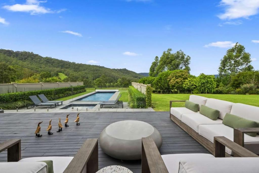 a patio with a white couch and a pool at Serendipity, Kangaroo Valley in Barrengarry
