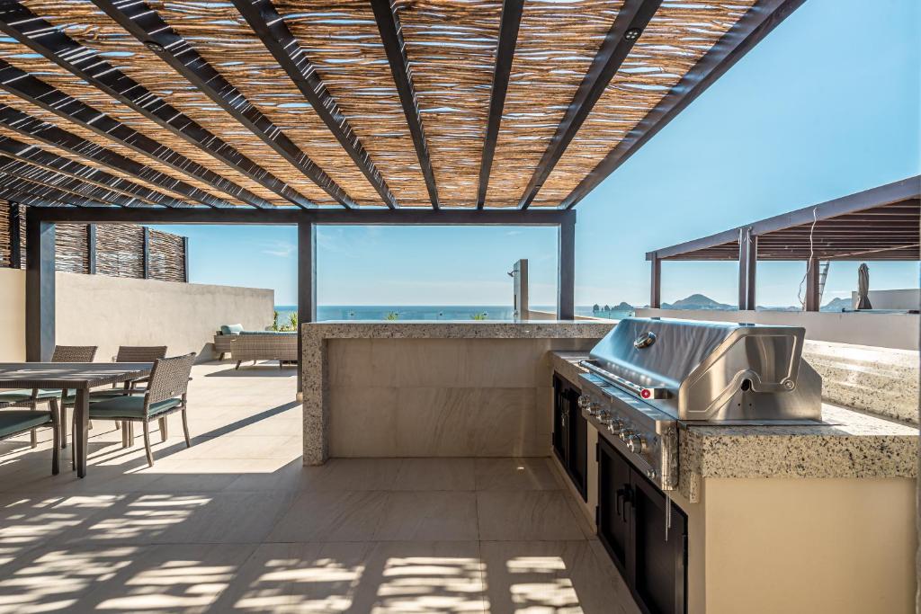 an outdoor kitchen with a grill and a table at Lumina at Vista Velas II Los Cabos in El Pueblito