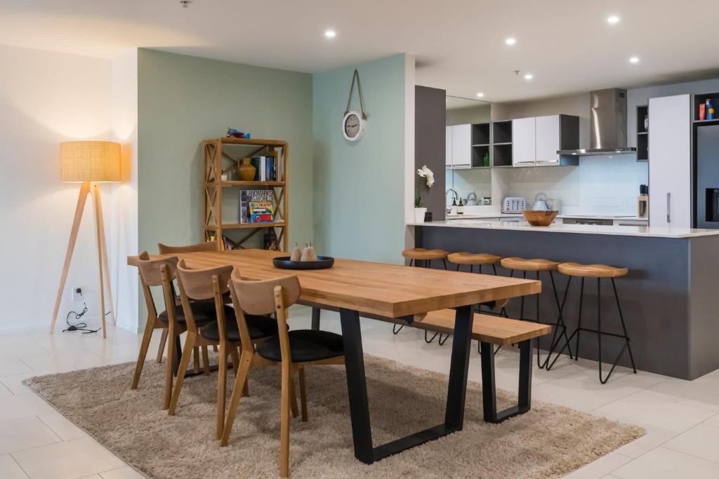 Una cocina y un comedor con mesa y sillas de madera. en Chilling at the Cayman, en Mount Maunganui