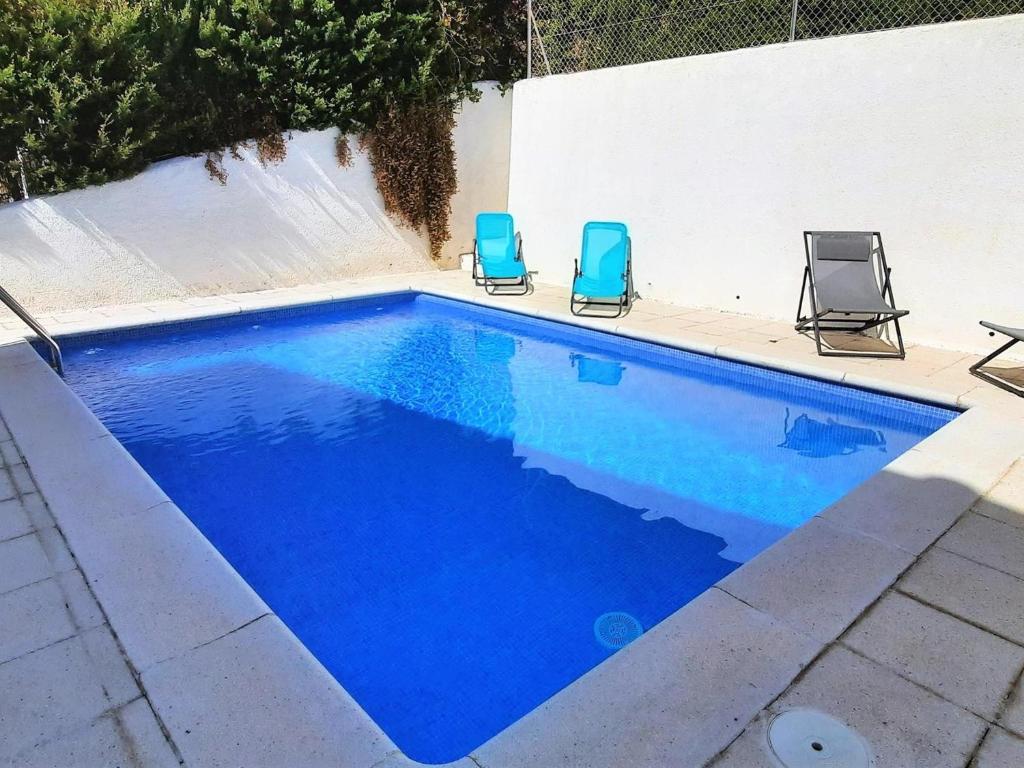 2 chaises et une piscine d'eau bleue dans l'établissement Apartamento Llançà, 3 dormitorios, 7 personas - ES-170-60, à Llançà