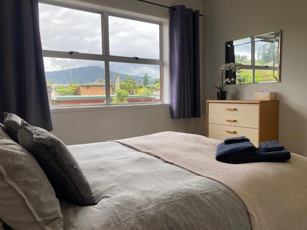 a bedroom with a bed with a dresser and a window at Family Adventure Get Away in Rotorua