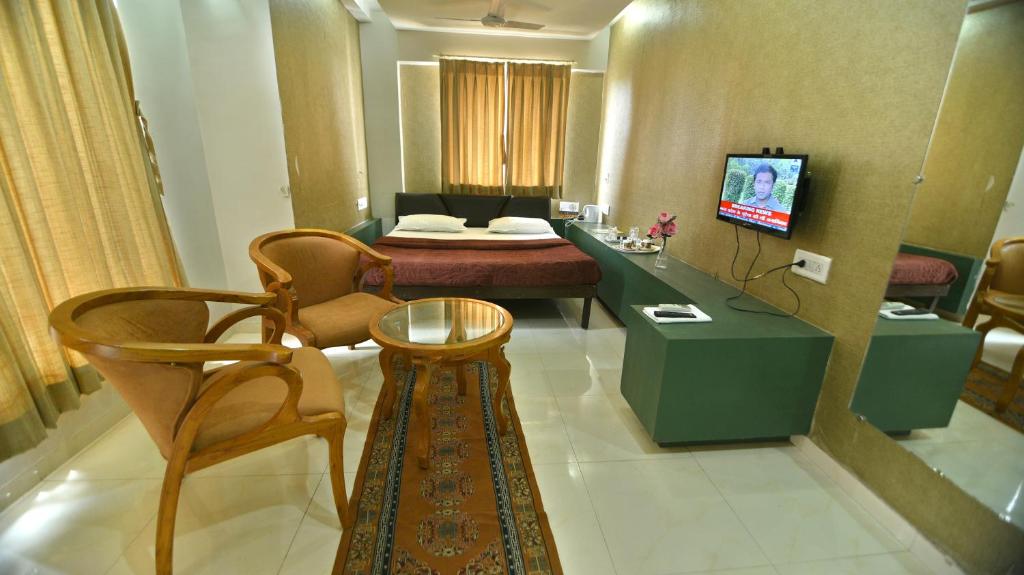 a hotel room with a bed and a table and chairs at Hotel Isher International in Gandhinagar