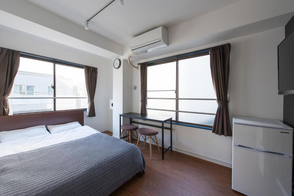 KandO Hostel Ueno في طوكيو: غرفة نوم بسرير ومكتب ونوافذ