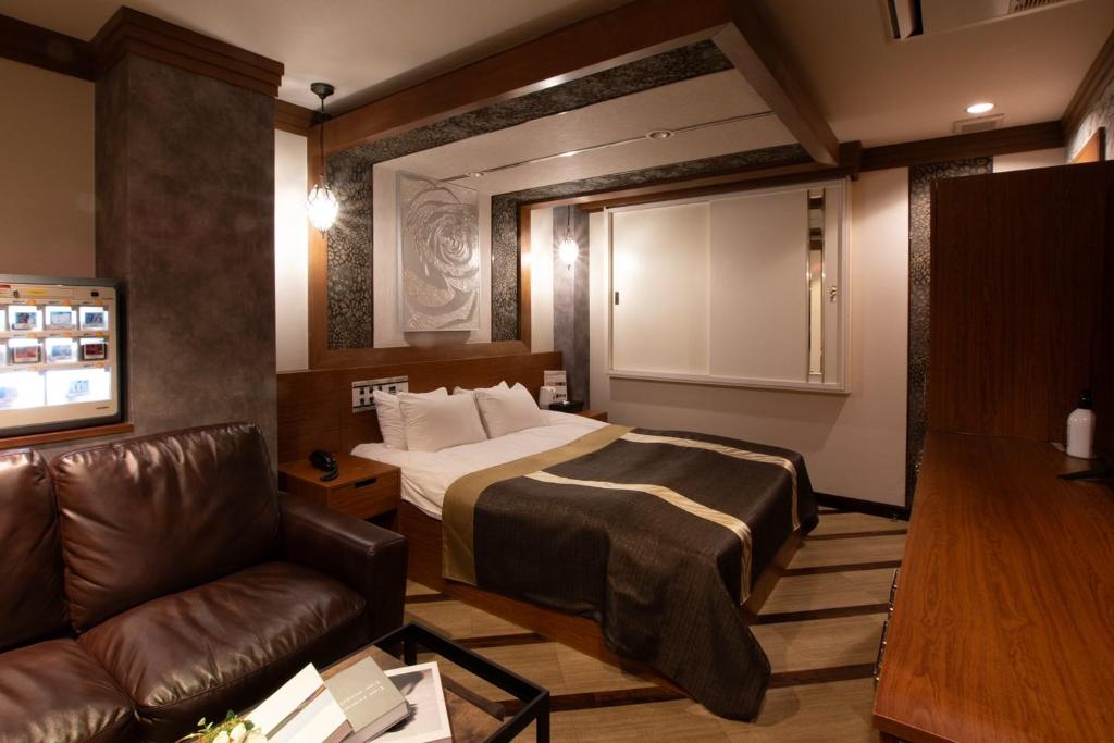 松戸市にあるHOTEL KSEA ( 大人専用）のベッドとソファ付きのホテルルーム
