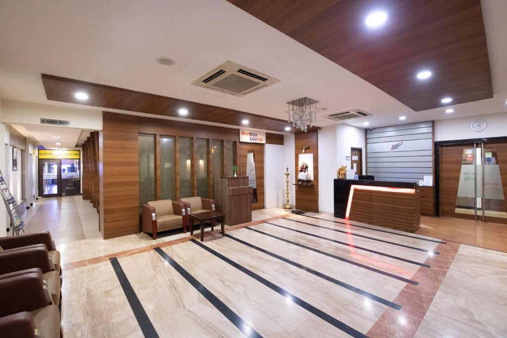 a lobby with a waiting area with a rug on the floor at Hotel High Point in Tiruchirappalli