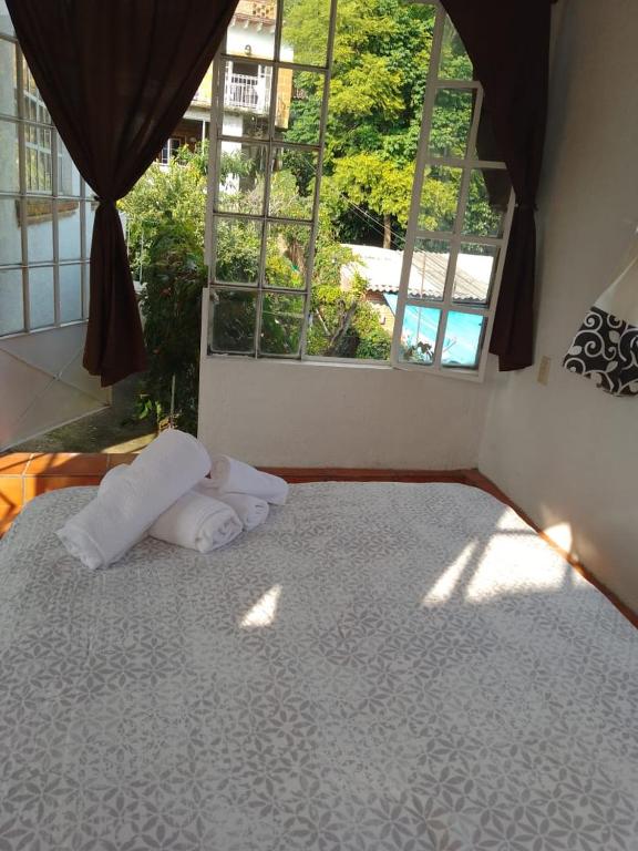 un letto con due cuscini in una stanza con finestra di Casa Sauces a Tepoztlán