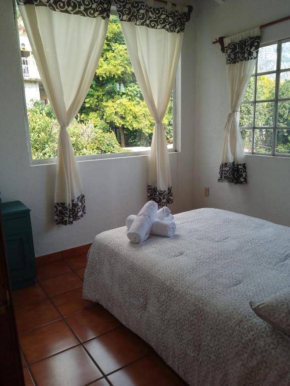 una camera da letto con un letto e due finestre di Casa Sauces a Tepoztlán