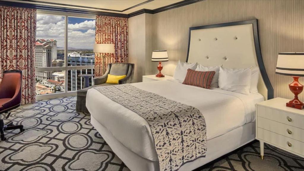 a hotel room with a large bed and a balcony at Paris Las Vegas Resort & Casino in Las Vegas