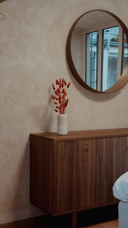 a mirror on top of a wooden cabinet with a plant on it at Atrium Apartments Aachen in Aachen