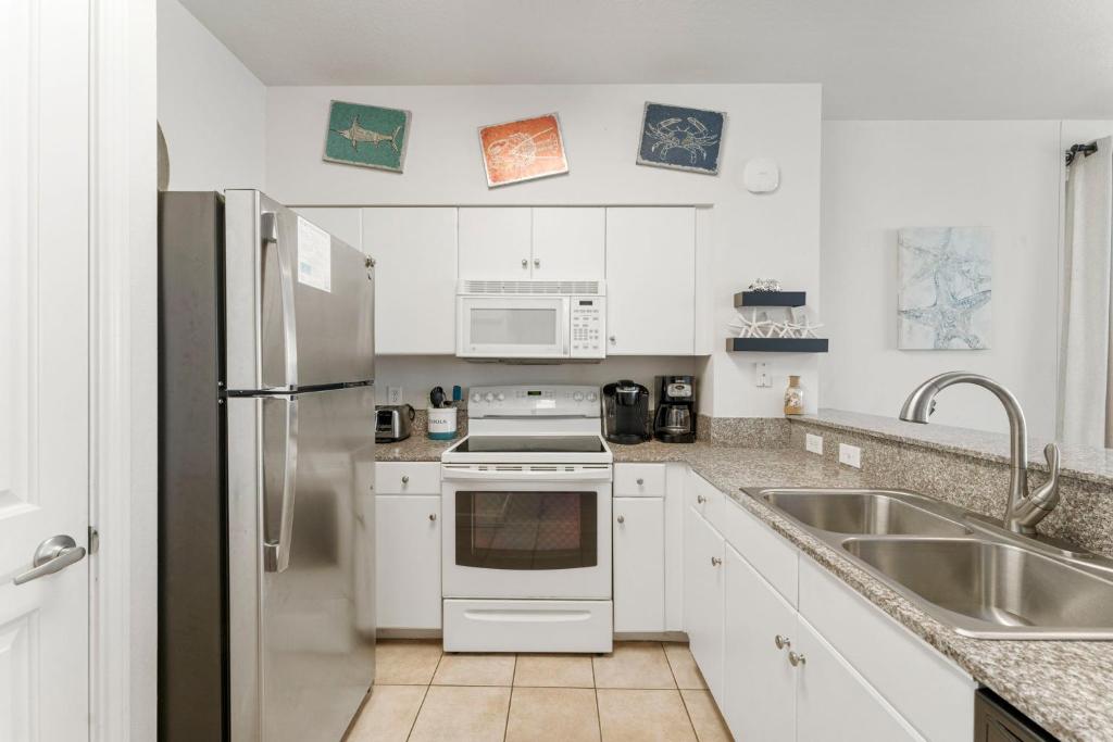 a white kitchen with a sink and a refrigerator at Shores Of Panama 1403 in Panama City Beach