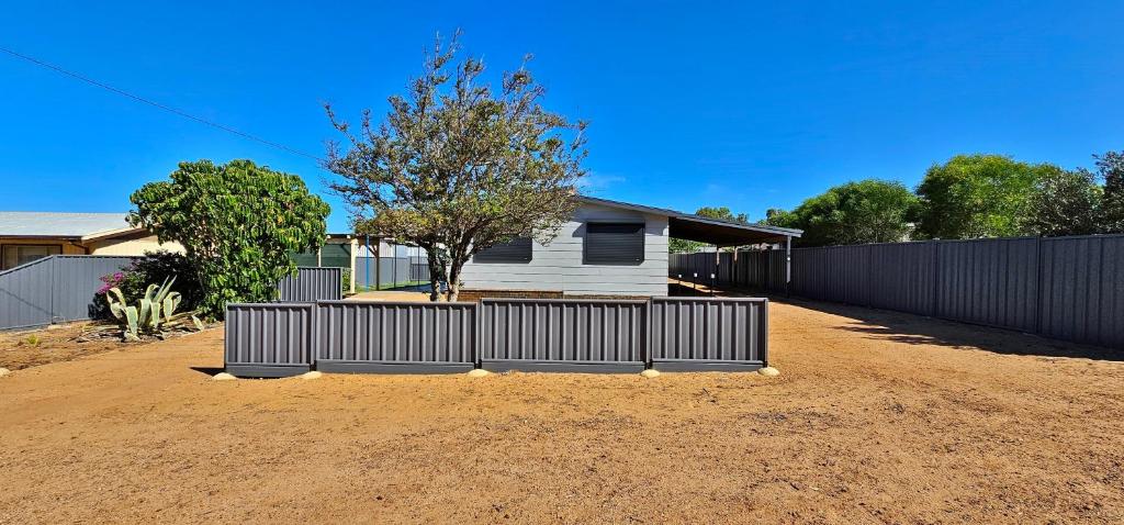 a house with a fence in front of a dirt yard at Patrick Crescent 18 - Kalbarri WA in Kalbarri