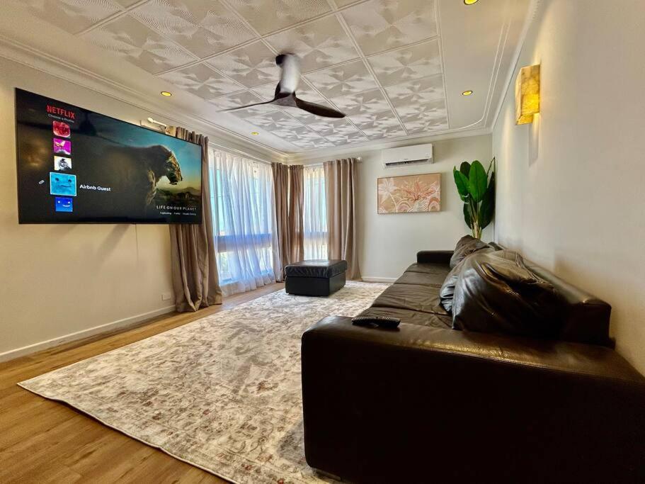 ein Wohnzimmer mit einem Sofa und einem TV in der Unterkunft The Wildflower- Luxury Home Stay in Utakarra