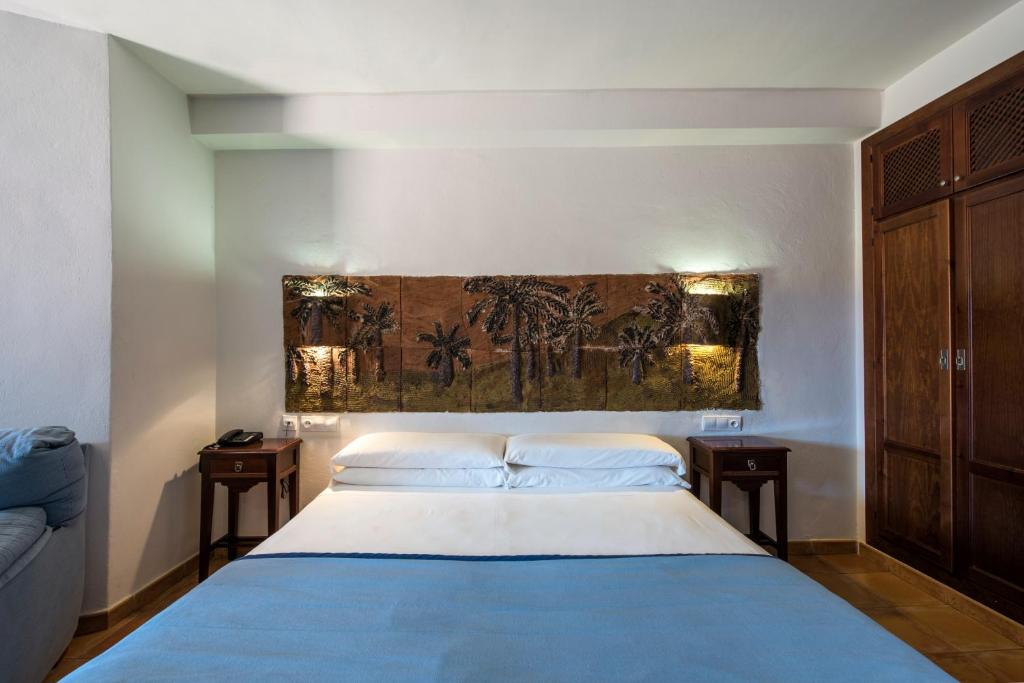 a bedroom with a blue bed with two night stands at Hotel de Naturaleza Rodalquilar & Spa Cabo de Gata in Rodalquilar