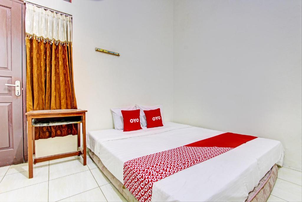a bedroom with a bed with red pillows on it at OYO 93208 Guest House Cemara 2 in Brebes