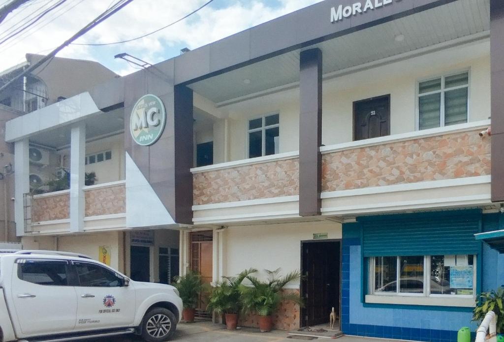 a white car parked in front of a building at RedDoorz @ Capitol View MC Inn Nueva Vizacaya in Bayombong