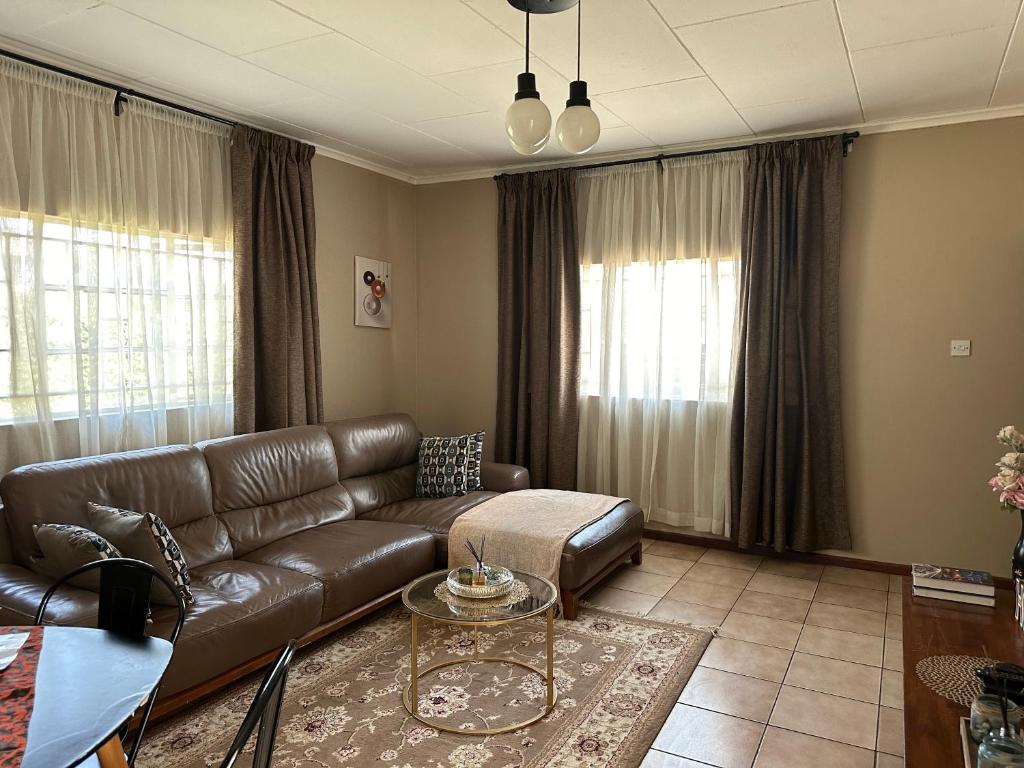 sala de estar con sofá de cuero y mesa en Serene 3 bedroom house in Olympia, Lusaka en Lusaka