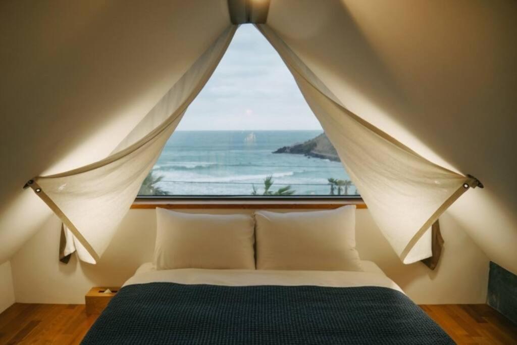 a bedroom with a bed with a large window at Yaho Beach House in Jeju
