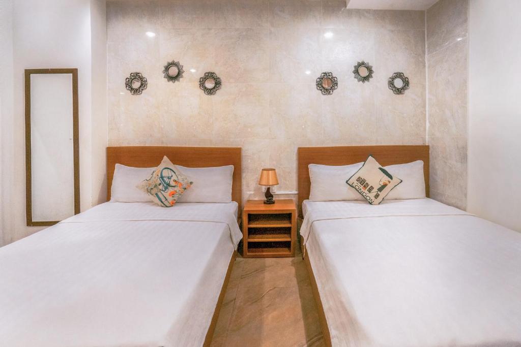 2 Einzelbetten in einem Zimmer mit einem Nachttisch in der Unterkunft C'Lavie Hotel - Saigon Airport Hotel in Ho-Chi-Minh-Stadt