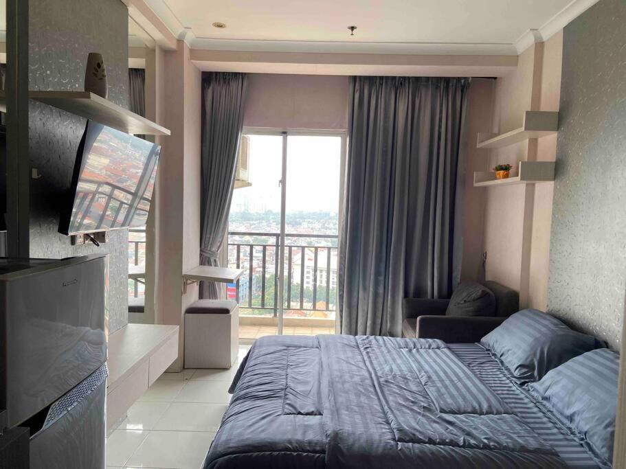 a bedroom with a bed and a large window at Apt Signature Park Studio H3r1 w/ Wi-Fi & Netflix in Jakarta