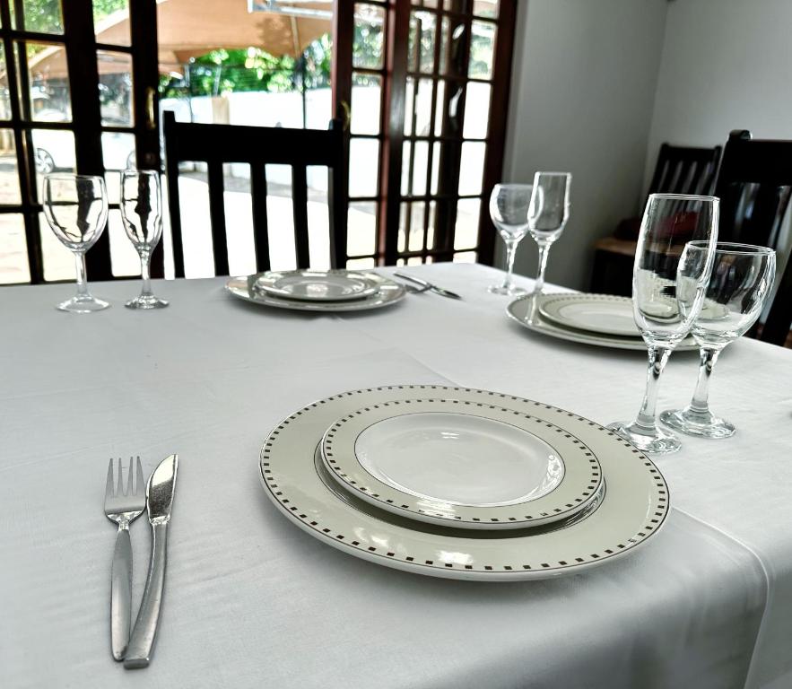 a table with plates and forks and wine glasses at The Hempel Guesthouse in Mokopane