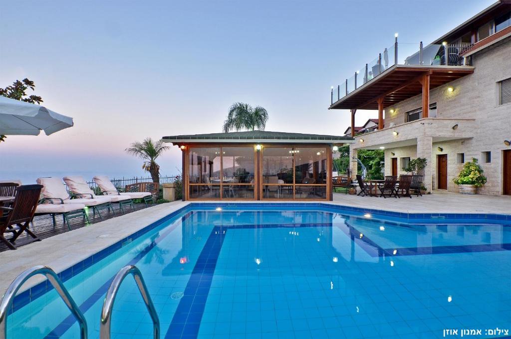 a swimming pool in front of a house at Rom Mansion in Rosh Pinna