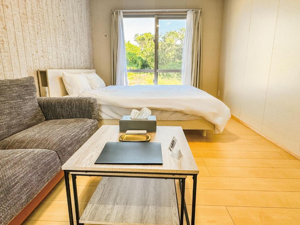 ein Wohnzimmer mit einem Bett und einem Couchtisch in der Unterkunft 与那国むんぶステイ空港前 in Sonai
