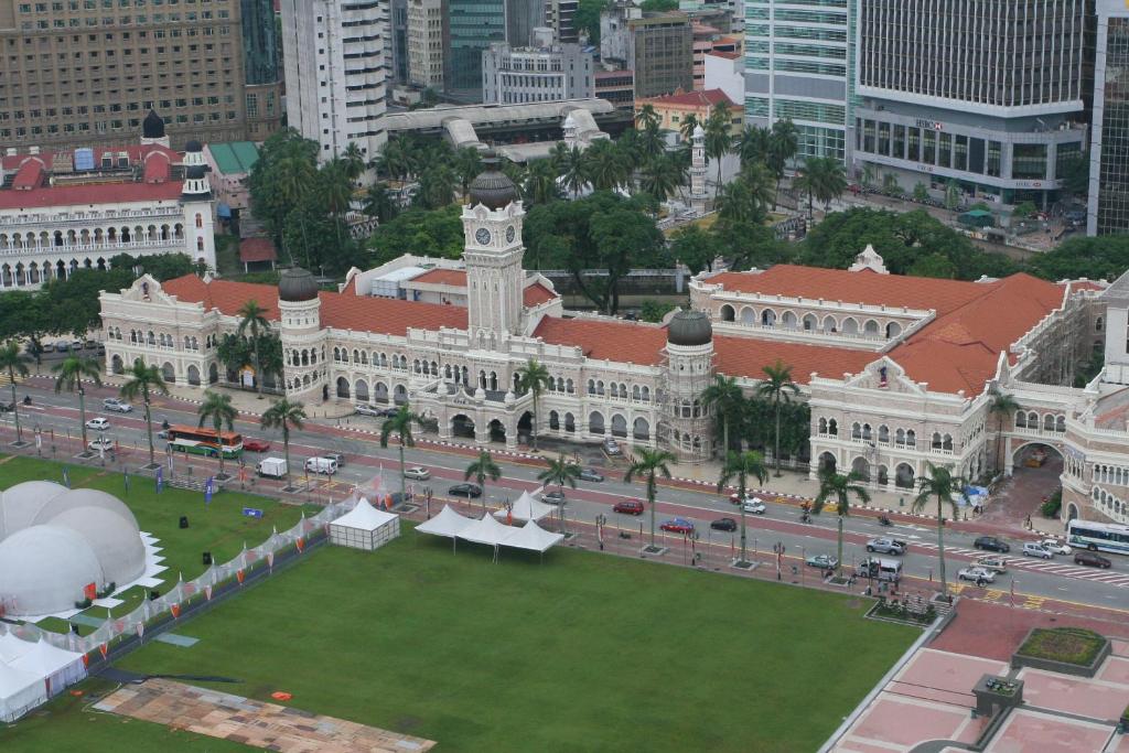 a large white building with a clock tower in a city at Swing & Pillows - Corona Inn Bukit Bintang in Kuala Lumpur