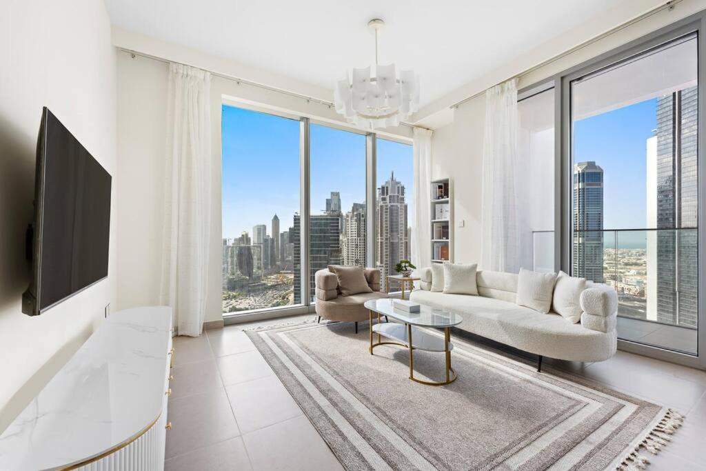 ein Wohnzimmer mit einem weißen Sofa und einem großen Fenster in der Unterkunft Lavish Forte Tower 2BR in the Heart of Downtown in Dubai