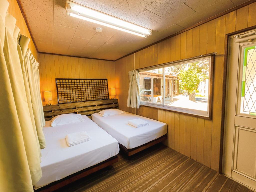 two beds in a room with a window at 与那国むんぶステイ祖納 in Sonai