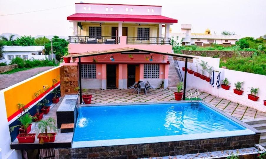 uma casa com piscina em frente a uma casa em Auspicious villa em Udaipur
