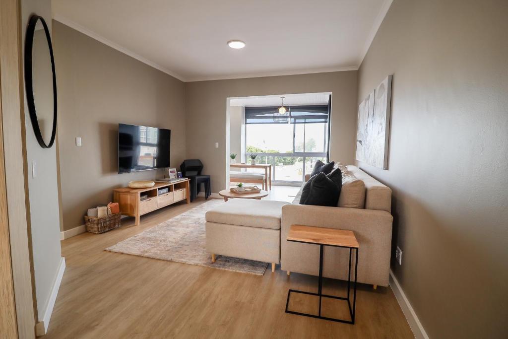 Una sala de estar con un sofá y un televisor. en Villa Fontana 7, en Yzerfontein