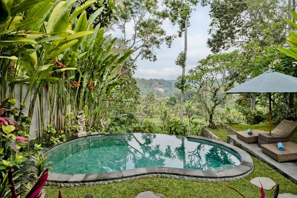 a swimming pool in the middle of a garden at Anandari Ubud Villa in Ubud
