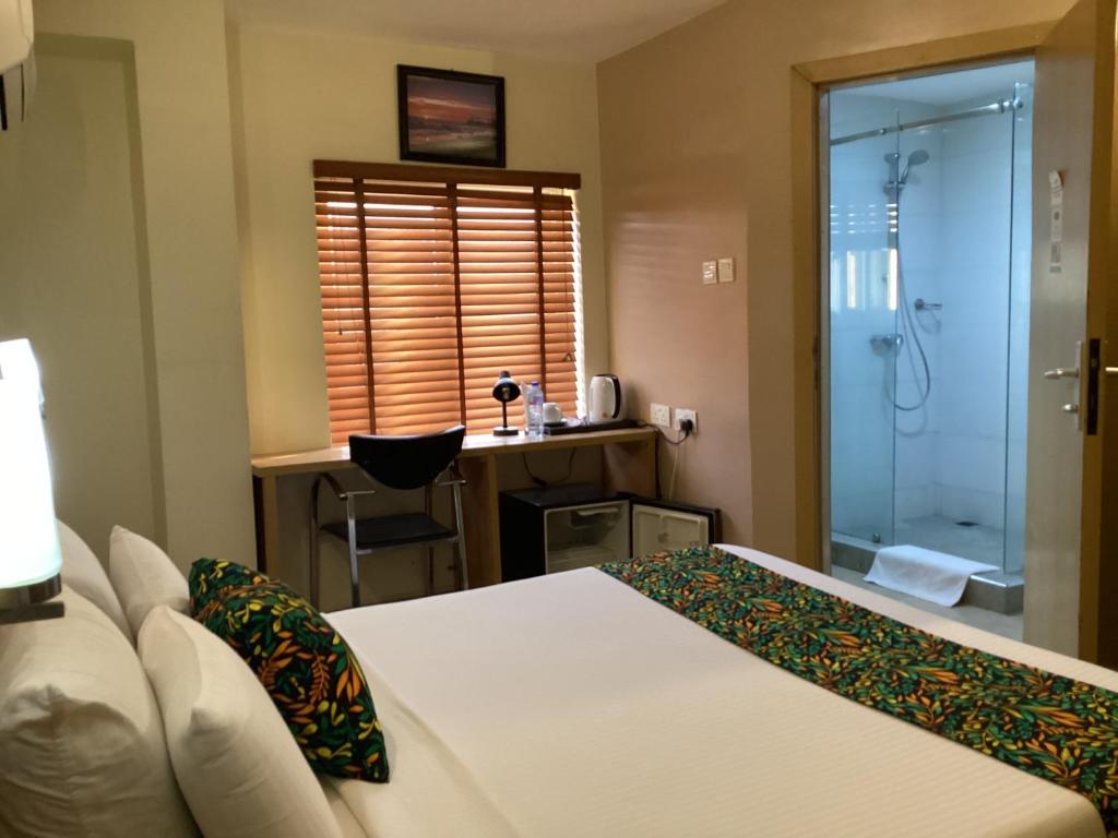 um quarto com uma cama e uma casa de banho com um chuveiro em Adis Hotels Ibadan em Ibadan