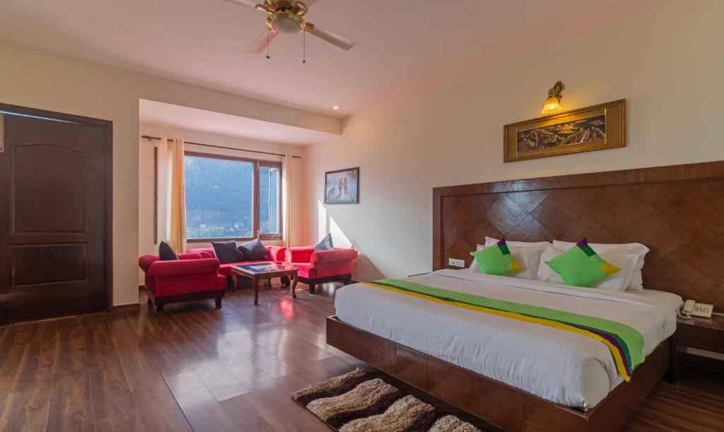 a bedroom with a large bed and red chairs at Treebo Trend Kapalin Resorts With Mountain View in Manāli