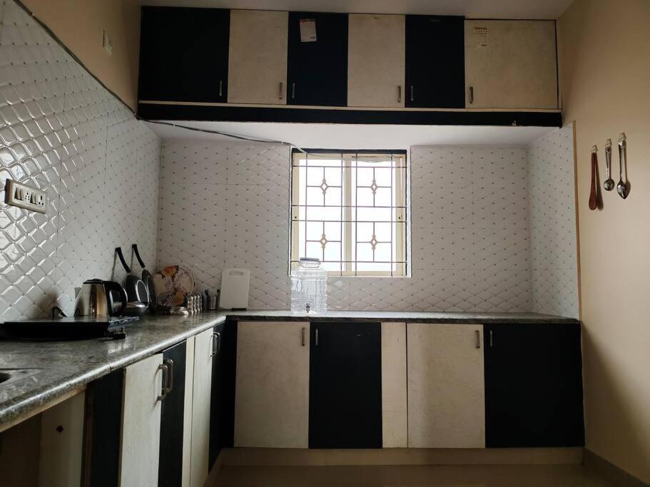 een keuken met zwart-witte kasten en een raam bij 2 BHK Apartment, Nova Blue 'A' in Bangalore