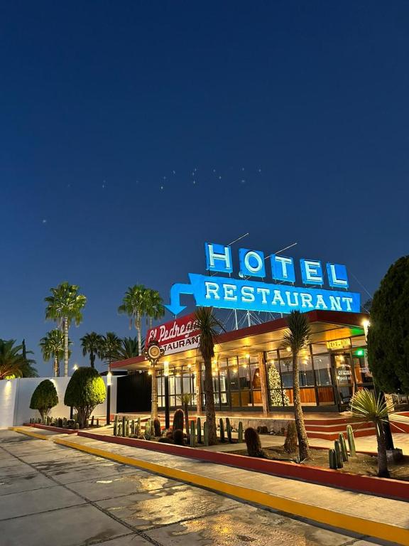 a hotel restaurant with a neon sign on a street at Hotel El Pedregal in Matehuala