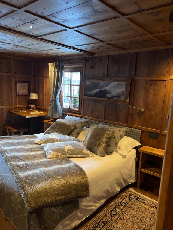 Cama grande en habitación con paredes de madera en Wongade Chambres d'hotes e Restaurant, en Gressoney-la-Trinité
