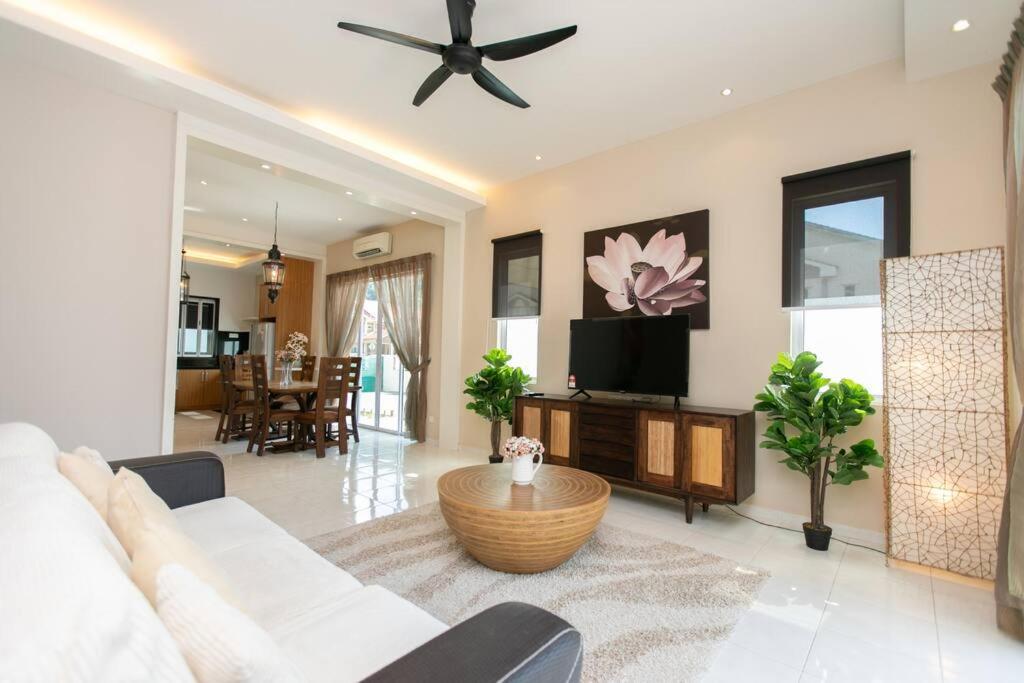 uma sala de estar com um sofá branco e uma televisão em BalikPulau Cozy Home 4BR w BBQ em Balik Pulau