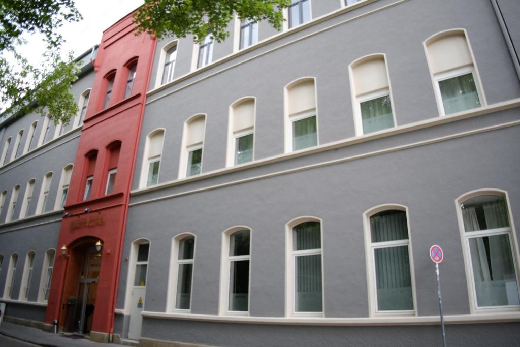 a gray building with white windows on a street at Amical Hotel in Wuppertal