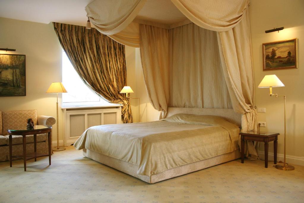 1 dormitorio con 1 cama con cortinas y ventana en Grand Hotel Fortecia, en Orsk