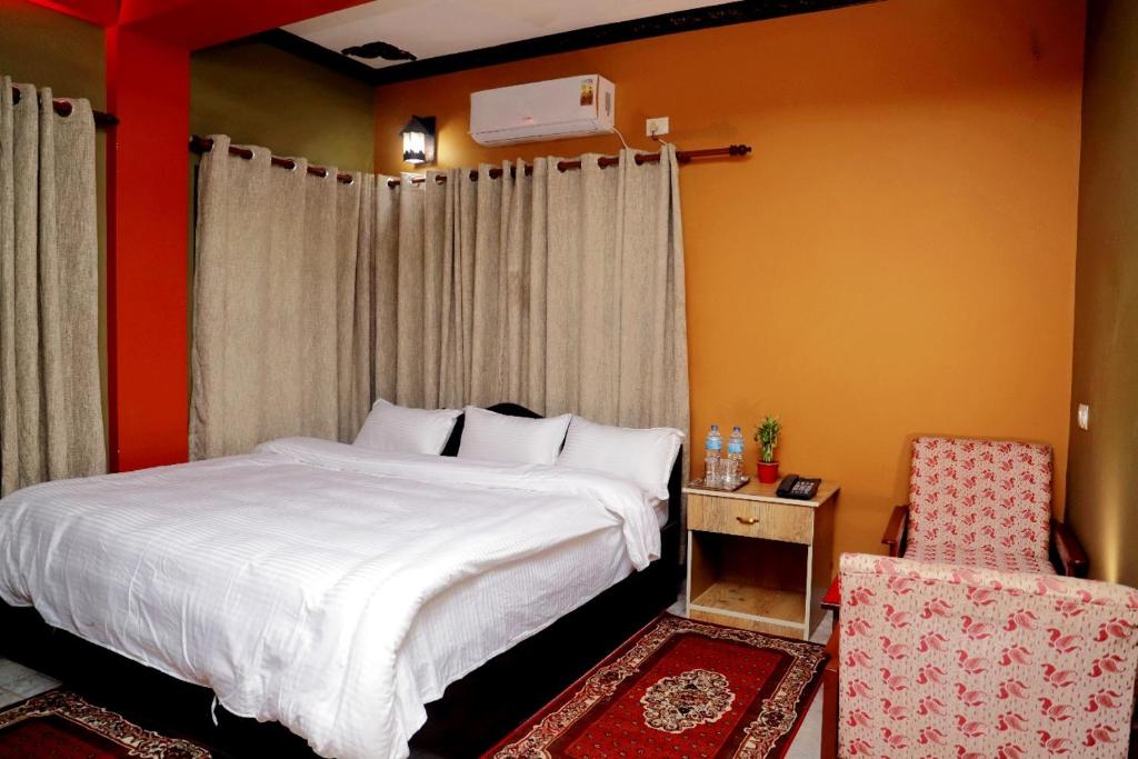 um quarto com uma cama branca e uma cadeira em Hotel Park Treasure em Chitwan