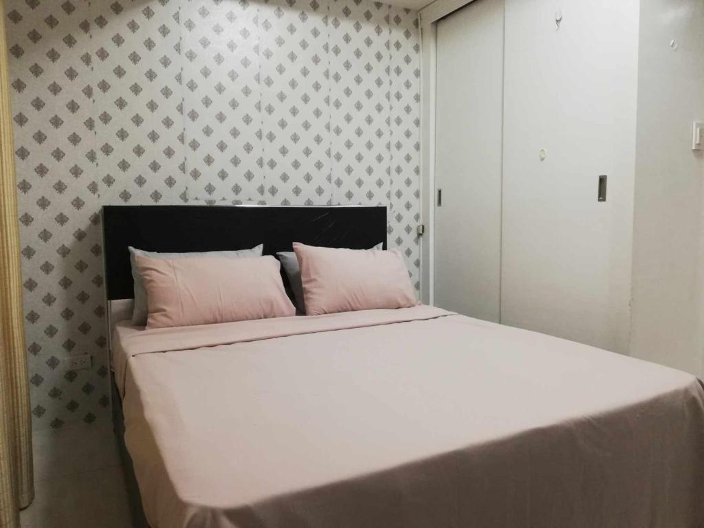 a bedroom with a large white bed with pink pillows at Grand Riviera suite Condotel in Manila