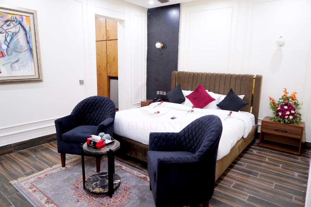 a hotel room with a bed and two chairs at Elegant Executive Suite in Multan
