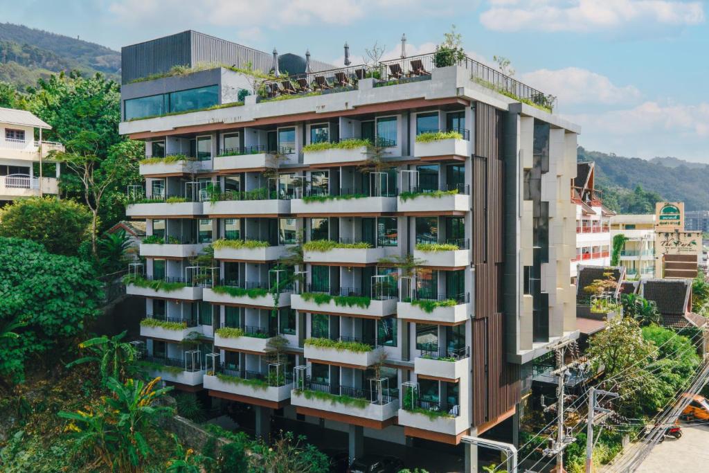 Rak Elegant Hotel Patong - SHA Extra Plus في شاطيء باتونغ: مبنى شقق فيه نباتات على البلكونات